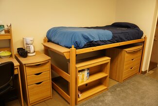 Bed with dressers and storage underneath, desk with drawers and rolling chair