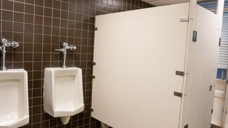Communal bathroom with urinals and private stalls