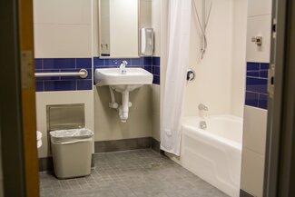 Single occupancy accessible bathroom with bathtub/shower combo, sink and toilet