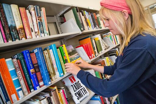 student looks through bookshelf