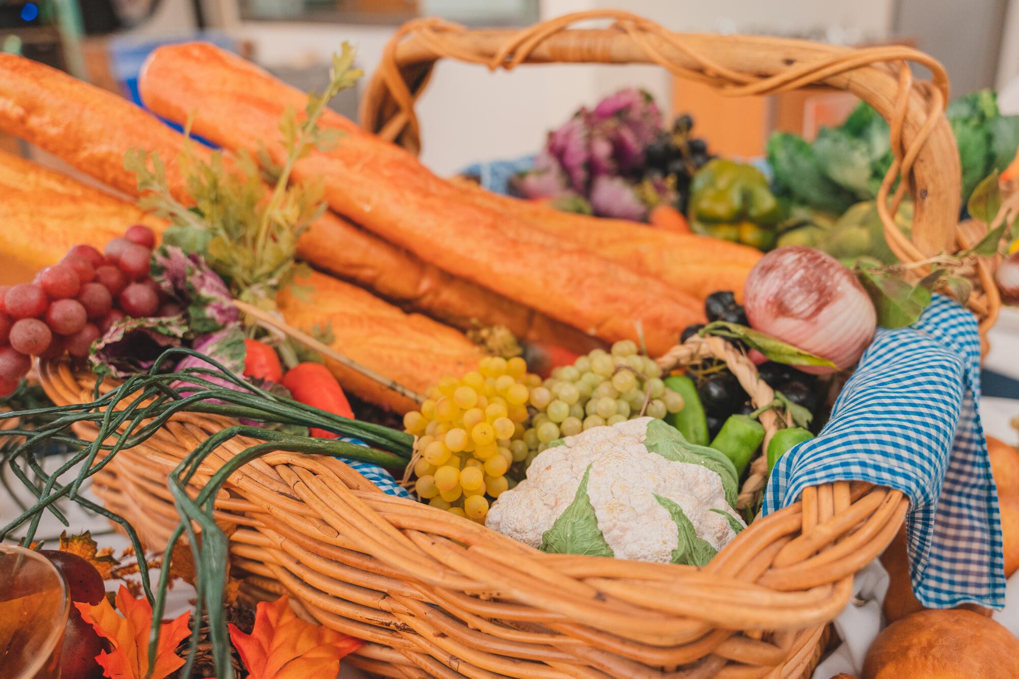 The brightly-colored image shows a variety of fruits and vegetables in baskets, plus bread and table decorations.